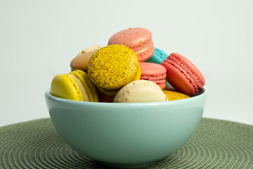 Colorful Macaroons in a bowl with a white and green background
