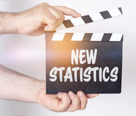 Obraz premium On a white background, a man holds a clapperboard in his hands on which it is written - NEW STATISTICS