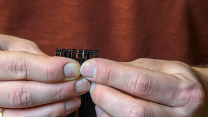 Closeup man hands hold PCI Express power supply connector for graphics card. Male fingers with nails without manicure