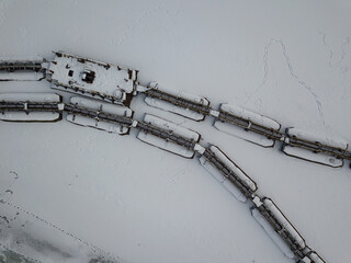 Metal gangways in a frozen industrial port. Aerial drone view. Winter snowy day.