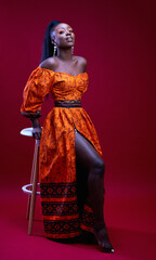 beautiful elegant african woman in traditional dress on red background, studio shot