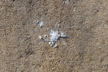 Tiny pile of rock salt on a sidewalk