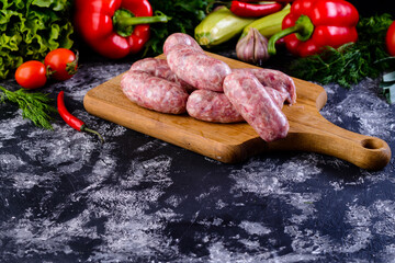 Fresh raw sausage on wooden board, Raw barbecue sausages with spices and vegetables. Top view...