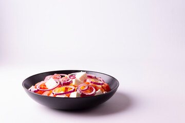 Greek salad in a black plate on a white plate. Horizontal orientation. View from above.