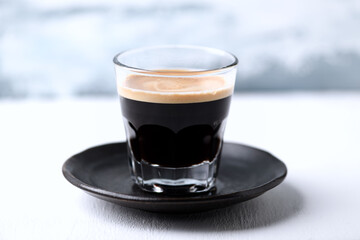 Coffee in glass cup on bright wooden background.