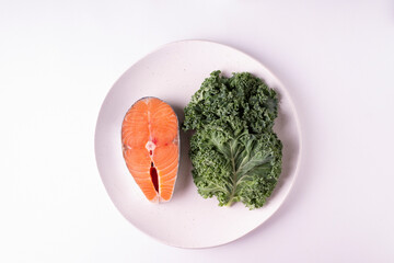 A piece of salmon and kale on a white background. Horizontal orientation. View from above.