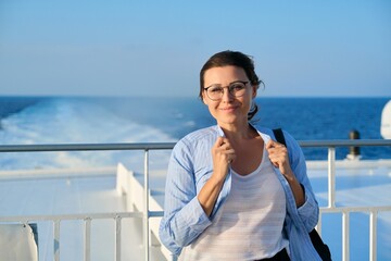 Happy middle aged woman on deck of cruise ship, copy space