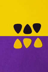 Guitar picks, placed on a half yellow half purple background