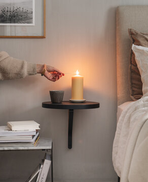 Frau z&uuml;ndet Kerze im Schlafzimmer an