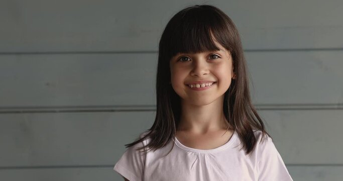 Head shot beautiful 10s girl pose in studio on wooden wall background. Child having attractive appearance, hairstyle with fringe smile look at camera. Generation z children, offspring portrait concept