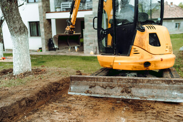 Fototapeta na wymiar Landscaping works at home construction site using excavator and mini bulldozer