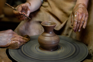 Pottery classes, student making clay pot on wheel. Close-up of dirty hands, sculpting clay crockery pottery training