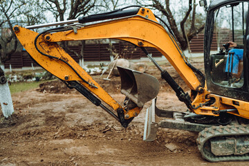 Landscaping works in the home garden at construction site with mini yellow excavator