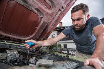 Young caucasian male is seen wrenching an engine or engine bay of an old vintage car. Tune up or...