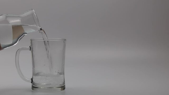 filling the empty glass with water on the white background. Space for text