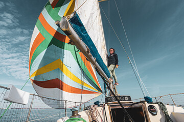 un homme en équilibre sur les voiles d'un bateau 