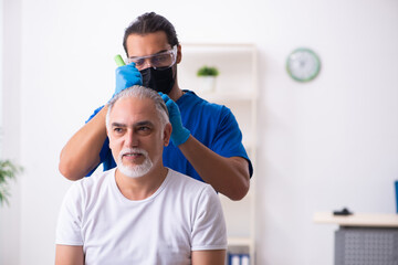 Old man visiting young male doctor in hair transplantation conce