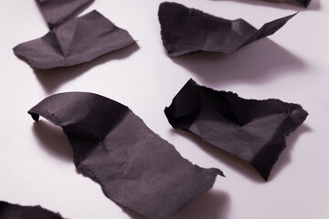 black crumpled paper torn to shreds lies on a white surface