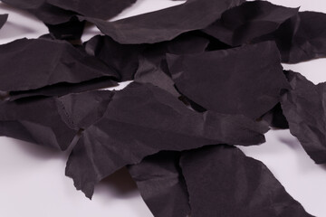 torn pieces of black crumpled paper piled up in a heap side angle view