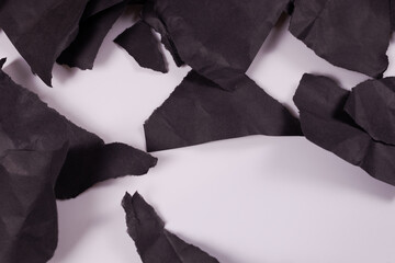 top view of black pieces of crumpled paper scattered chaotically