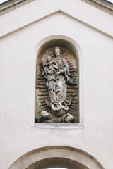Fototapeta na wymiar A sculpture of St. Mary with the baby Jesus piercing a serpent with a spear in a niche on the facade of the Armenian Catholic Church in Lvov, Ukraine.