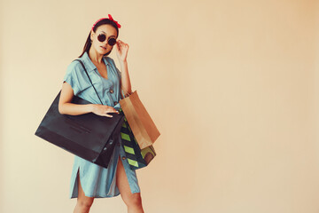 Girl with shopping bags. Lady on a yellow background. Woman in a blue dress.