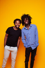 Obraz premium two african american guys posing cheerful together on yellow background, lifestyle people concept