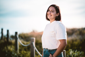 chica joven morena con vaqueros azules y camisa blanca sonriendo retrato