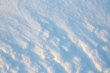 Beautiful winter background with snowy ground. Natural snow texture. Wind sculpted patterns on snow surface.