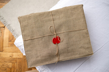 Box tied with linen rope and an ink seal lie on table, package in linen cloth sealed with sealing...
