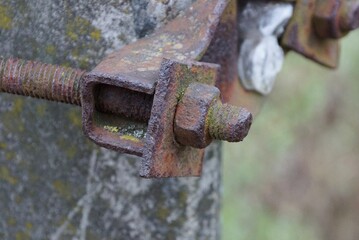 old long rusty brown metal construction from a nut and a bolt on plates of a beam in the street