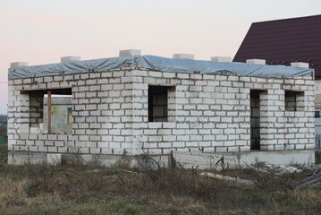 Fototapeta premium a large unfinished private house made of white bricks in the street on gray dry grass