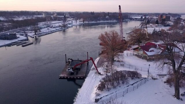 Pull-away aerial of a construction barge working on a port during winter.