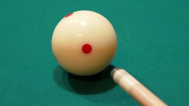 Billiards Closeup of White Cue Ball with Red Spots being Shot on a Pool Table by Wooden Cue Stick Tip Digging into Green Felt after Several Practice Strokes, No Faces