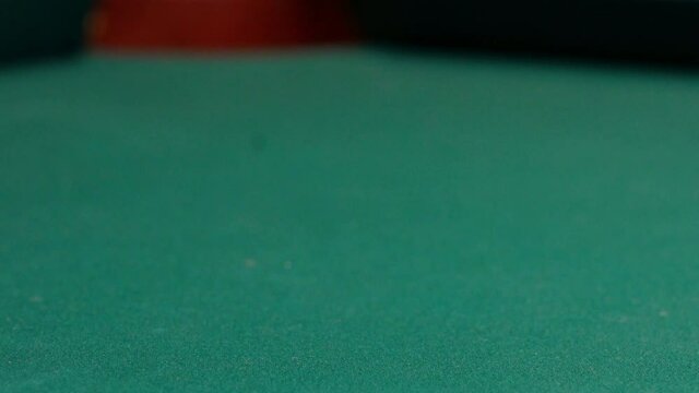 Closeup of Yellow Striped Nine Ball Being Shot into the Corner Pocket of a Brunswick Pool Table by Cue Ball with Red Spots Rolling Out of Frame, Green Felt or Cloth and No Faces