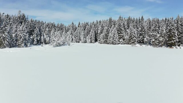 Flying above frozen and snow covered lake in winter, Crno jezero or Black Lake on Pohorje, Slovenia