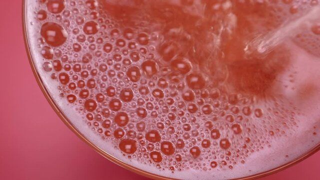 Closeup of glass with sparkling rose wine decorated gold star confetti, celebration party on pink background