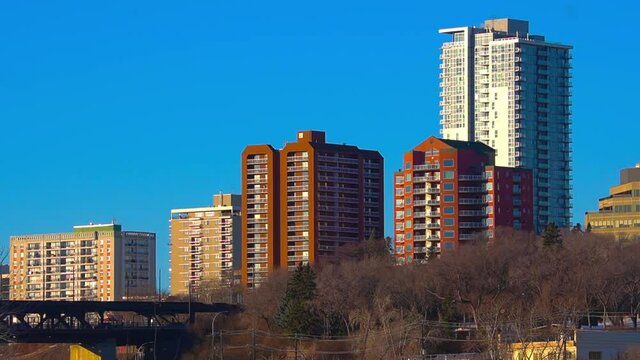 4k Stunning Blue clear sunny afternoon sklyline closeup of post modern apartment buildings towering over older condominiums by river valley of downtown Edmonton next to historic high level bridge