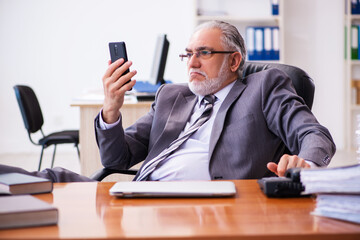 Old male businessman employee working in the office