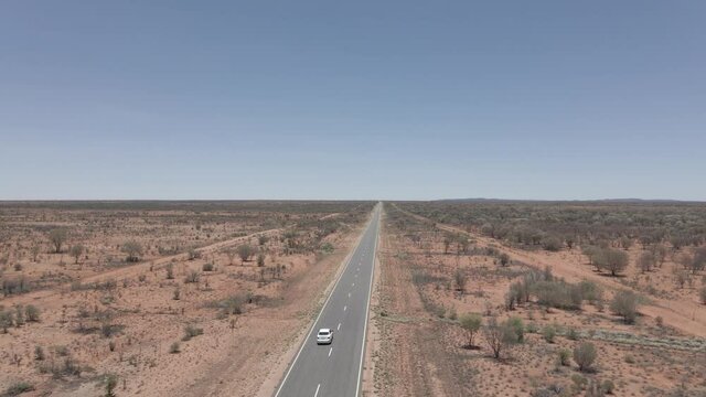 Van Driving On Long And Winding Uluru Road. Northern Territory Of Australia. Drone Pull-away