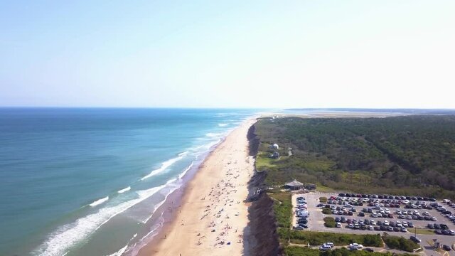 Cars Parked On The Seaside Parking Lot With Tourists Enjoying Nauset Light Beach In Summer In Eastham, Massachusetts. - aerial sideways