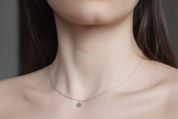 Woman neck and chin. Silver necklace with trefoil pendant