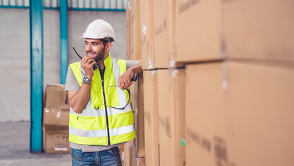 Professional cargo worker talks on portable radio to contact another worker . Factory and warehouse...