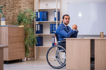 Young male employee in wheel-chair working in the office