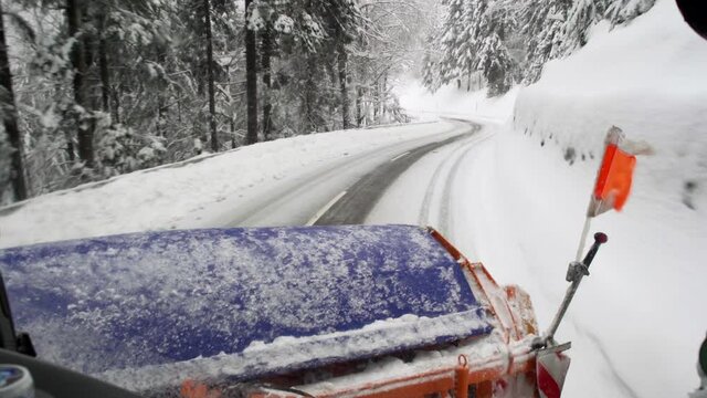 Snow plow clears snowy road at mountain road. view out of drivers cab.