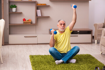 Fototapeta na wymiar Aged man doing sport exercises at home
