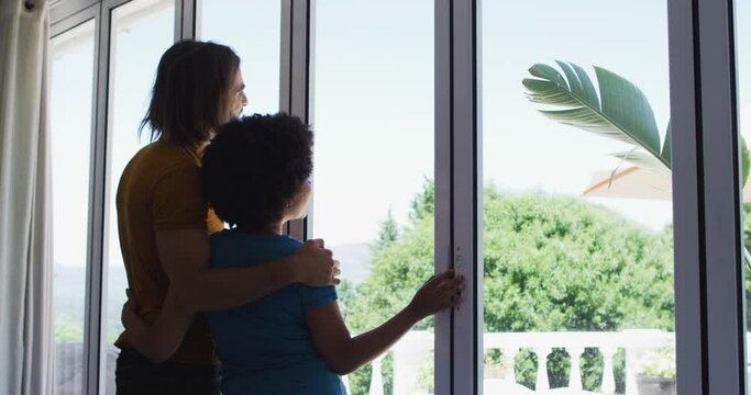 Mixed race couple looking out of the window at home
