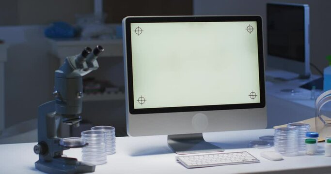 Desktop computer with illuminated screen at a workstation in an empty laboratory
