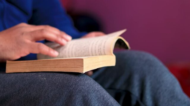 Concept of reading novel at home. Male turns pages of old novel book.