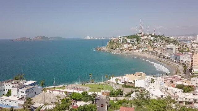 Aerial drone dolly shot above coast shore city Mazatlan, Sinaloa, Mexico with sea ocean view. Flying along the beach seashore in latin america with houses and hotels.